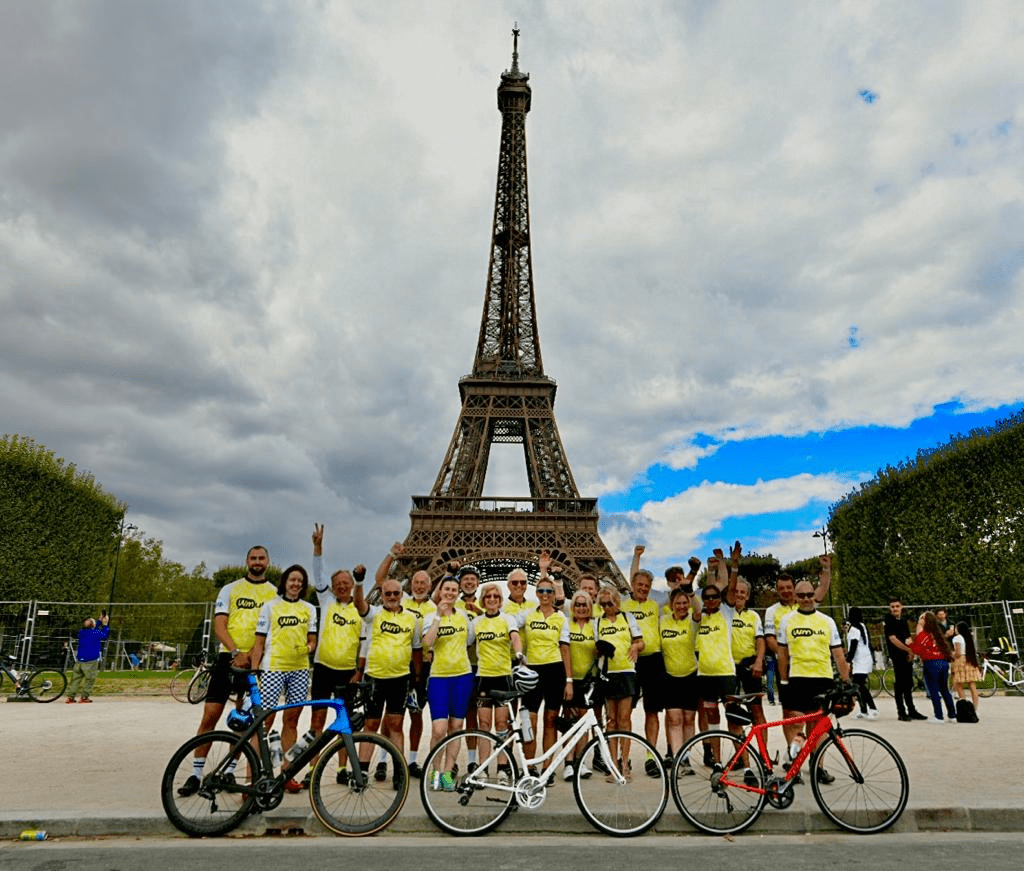 A group of people in yellow "WMUK" shirts posing in front of the Eiffel Tower.